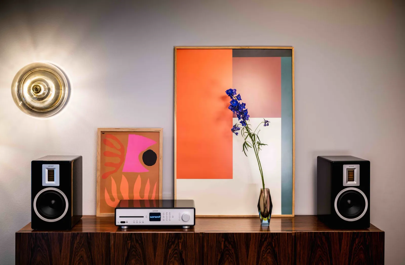 Schwarze Regallautsprecher mit Audiogerät auf einem dunklen Sideboard