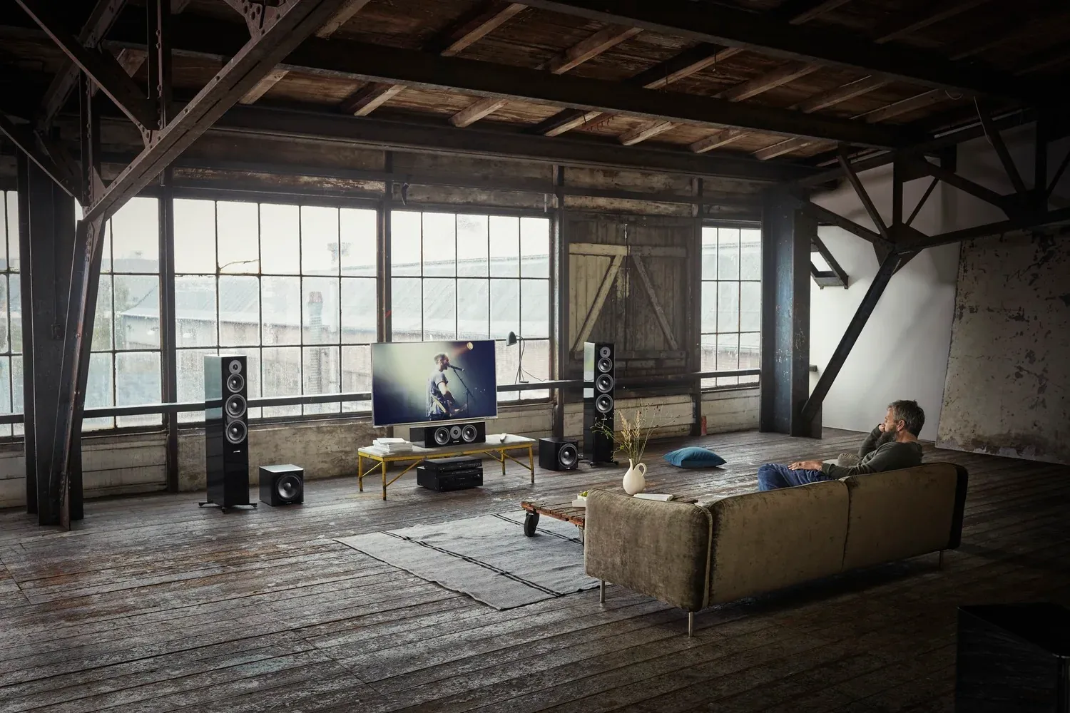 Loft mit Heimkino-Aufbau, ein Mann sitzt auf dem Sofa