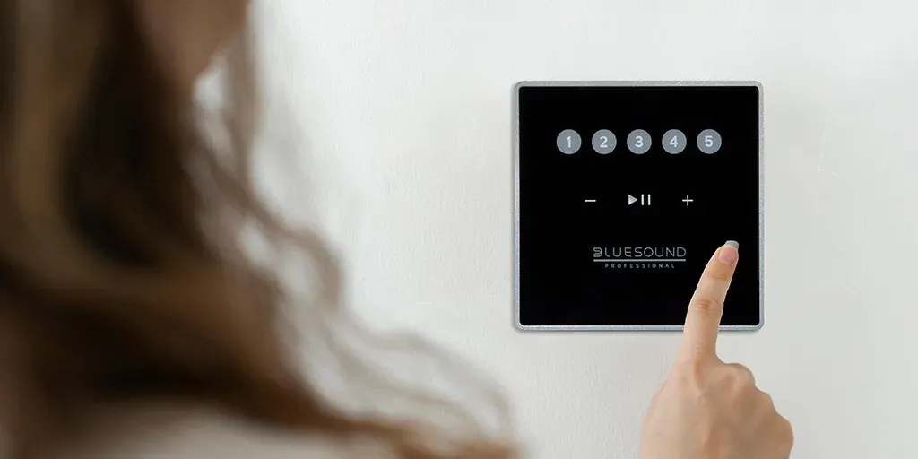 Hand bedient ein Bluesound-Professional-Wandbedienteil