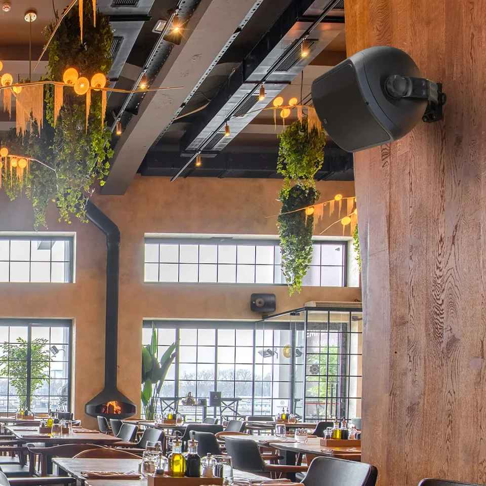 Restaurant mit schwarzem Wandlautsprecher an einem Holzbalken