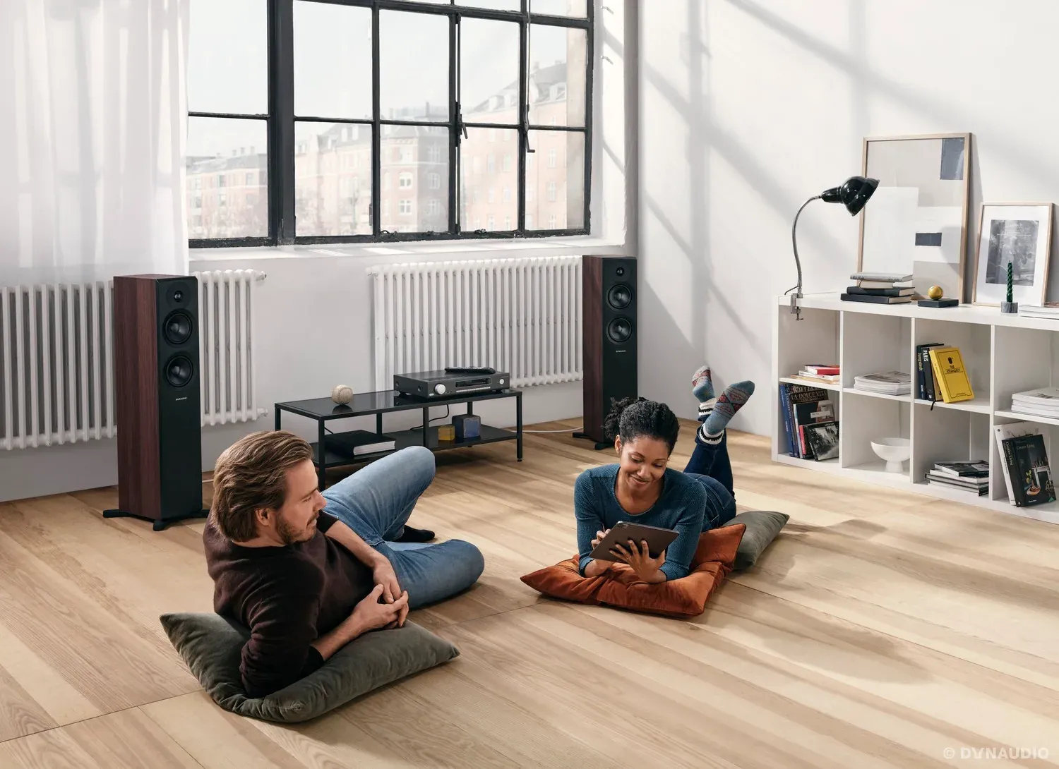 Paar liegt auf dem Boden vor Standlautsprechern in einem hellen Loft