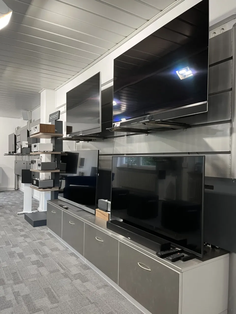 Ausstellungswand mit mehreren Fernsehern und Regalen im Showroom