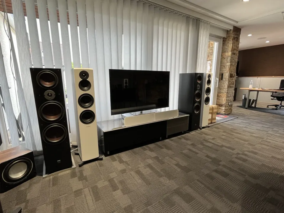 Showroom des Musik Studios: dunkle und helle Standlautsprecher neben einem Fernseher auf Lowboard