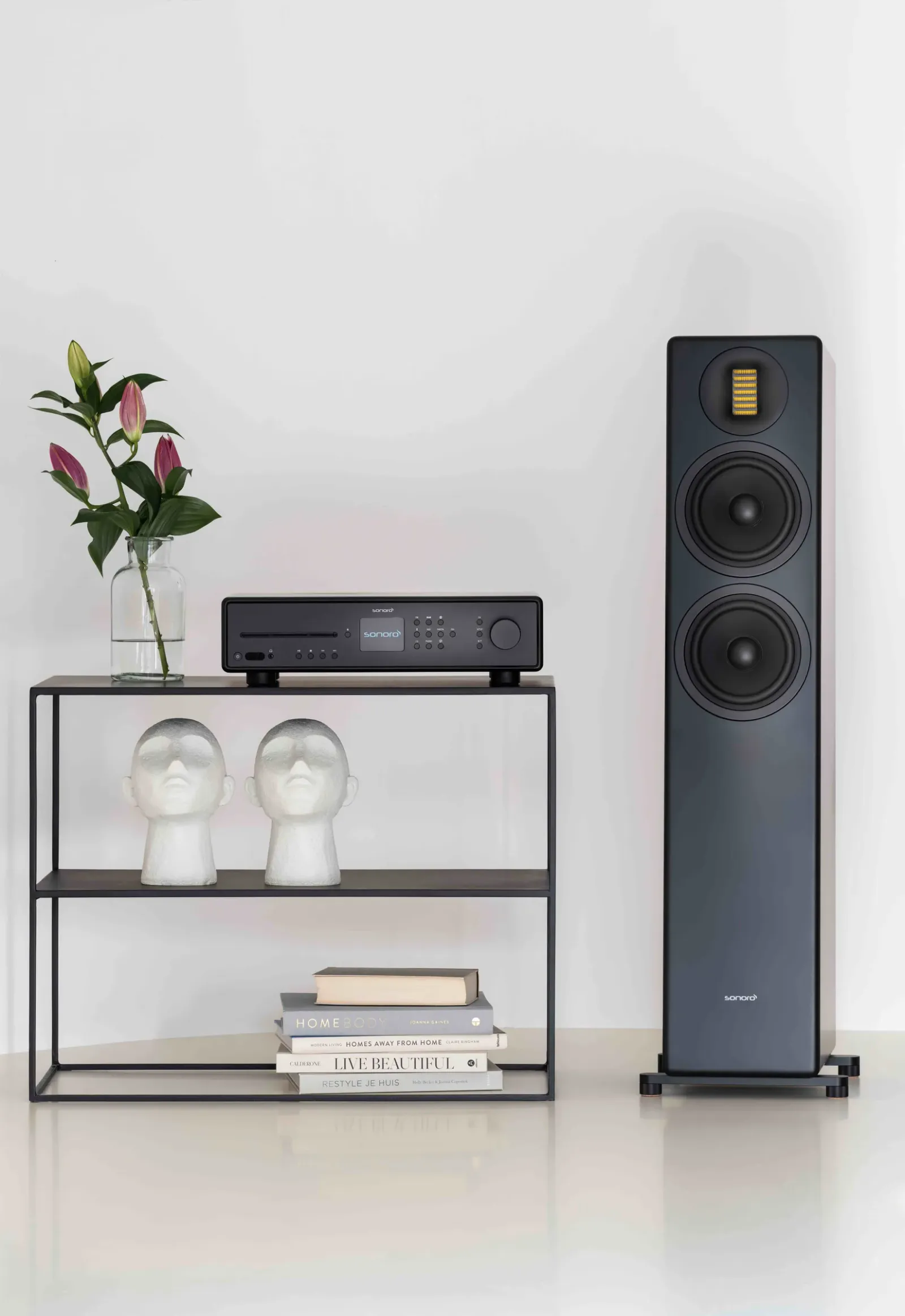 Dunkler Standlautsprecher neben einem Regal mit Audiogerät