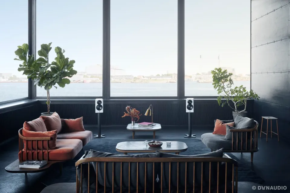 Loft-Wohnzimmer mit Blick aufs Wasser und zwei Regallautsprechern auf Ständern