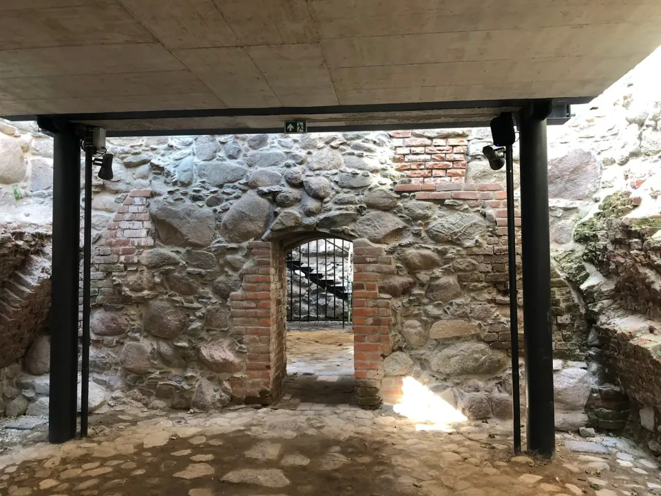 Überdachter Außenbereich mit Lautsprechern an Stahlträgern vor einer Natursteinmauer